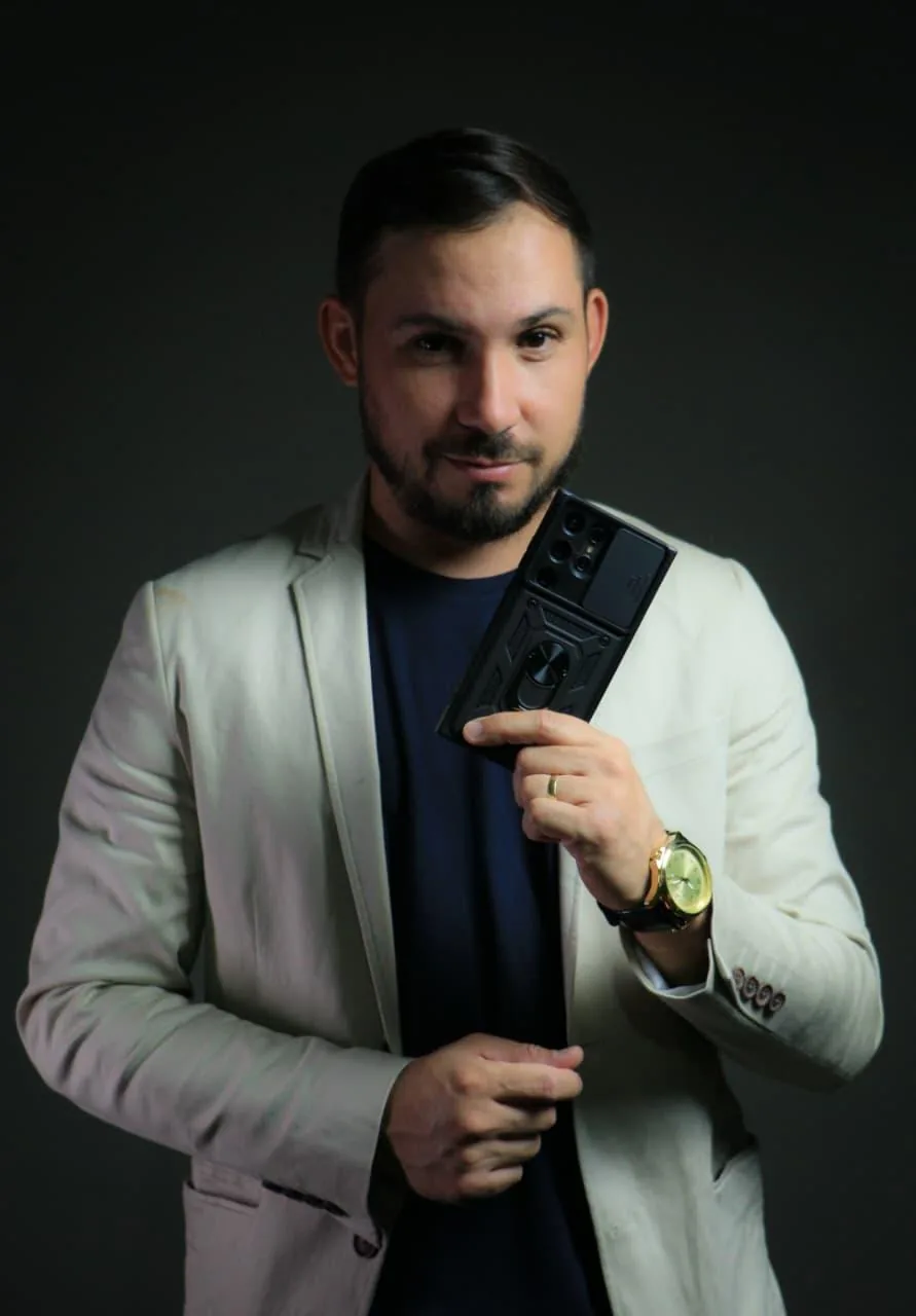 Luan Silva de blazer bege, com o celular na mão